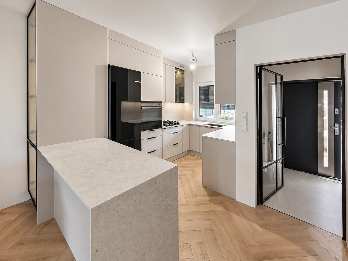 Kuchnia od strony salonu z dodatkowym blatem Dekton Sabbia, wysoką zabudową i czarnymi detalami.
